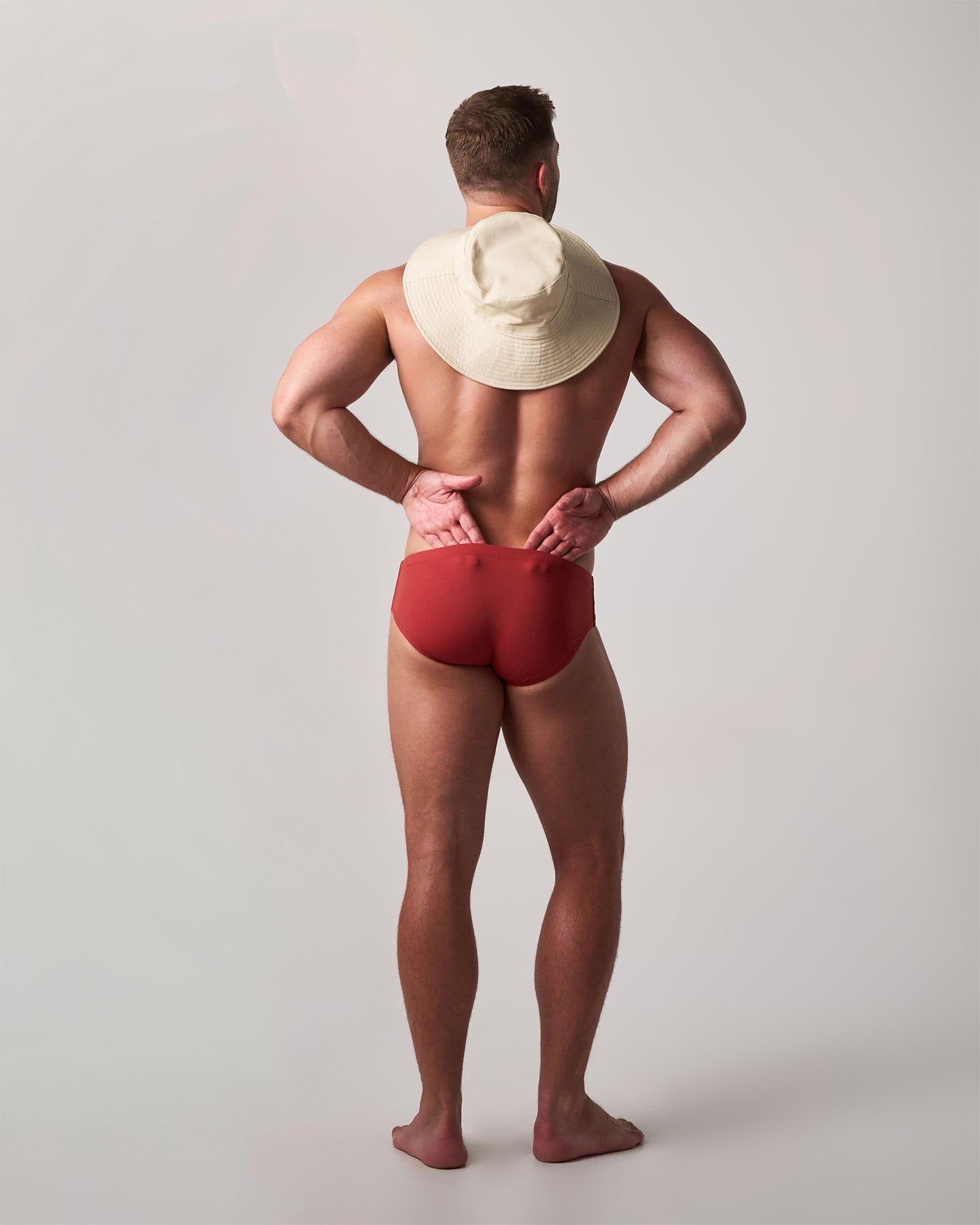 Man wearing a red swimsuit and white hat on a plain background