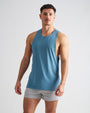 Man wearing a blue tank top and gray shorts on a white background